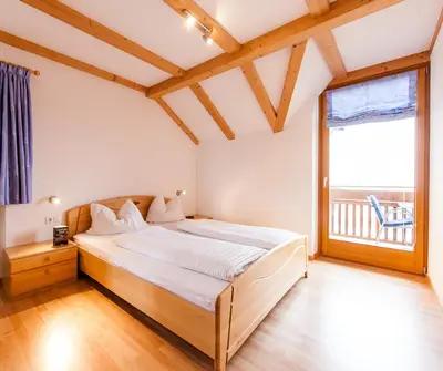 a bedroom with a large bed and a large window at Weinhof Kager in Missiano
