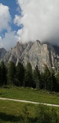 a mountain with clouds on top of it in a field at Casa Righini in Moena