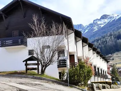 a building with a tree in front of a mountain at Casa Righini in Moena
