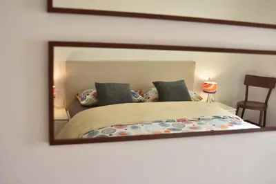a mirror on a wall with a bed in a room at T&B MOUNTAIN VIEW in Monguelfo