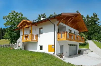 a white house with wooden balconies on it at Pichlerhof in Avelengo