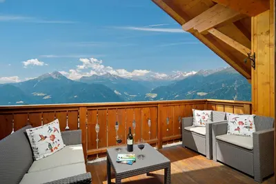 a balcony with chairs and a table and mountains at Pichlerhof in Avelengo