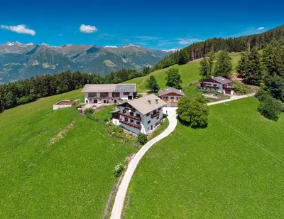 an aerial view of a house on a green hill at Pichlerhof in Avelengo