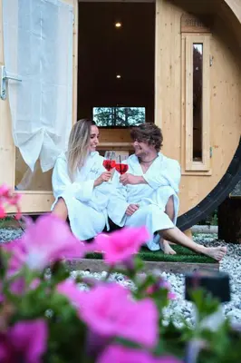 a man and woman sitting on a porch drinking wine at Camping Marmolada Malga Ciapela - Glamping Experience in Malga Ciapela