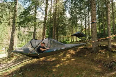 a man in a tent in the woods at Camping Marmolada Malga Ciapela - Glamping Experience in Malga Ciapela