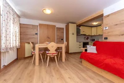 a living room with a table and a red couch at Casa Caviola Centro in Falcade