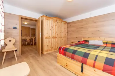 a bedroom with a bed and wooden walls at Casa Caviola Centro in Falcade