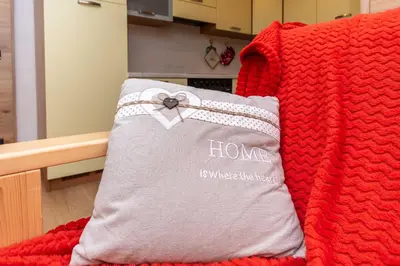 a red blanket with a pillow with the word home on it at Casa Caviola Centro in Falcade