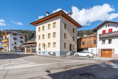 a white building with a brown roof on a street at Casa Caviola Centro in Falcade