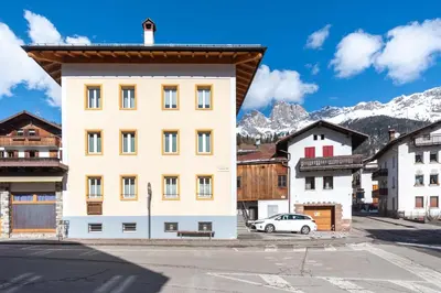 a building in a town with mountains in the background at Casa Caviola Centro in Falcade
