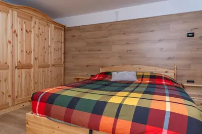a bedroom with wooden walls and a colorful bed at Casa Caviola Centro in Falcade