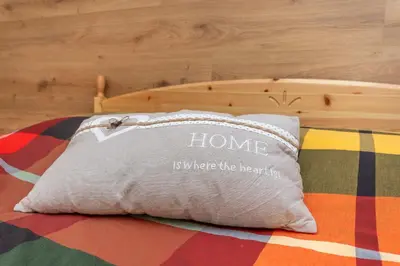 a pillow with the words home is where the heart is at Casa Caviola Centro in Falcade