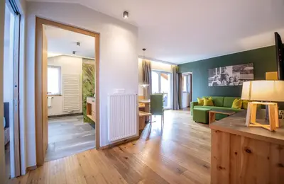 a living room with a green couch and a mirror at Hotel DAS ROYAL in Obereggen in Obereggen