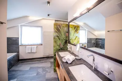 a bathroom with a sink and a tub and a mirror at Hotel DAS ROYAL in Obereggen in Obereggen