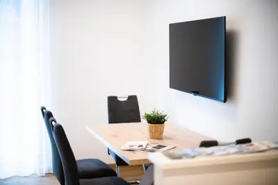a dining room table with a television on a wall at Stay City in MeranO with Bio Sauna in Merano