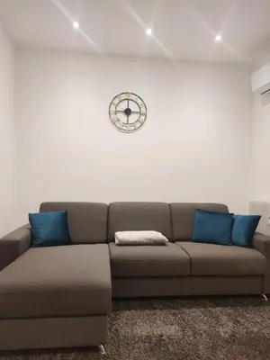 a living room with a couch and a clock on the wall at Stay City in MeranO with Bio Sauna in Merano