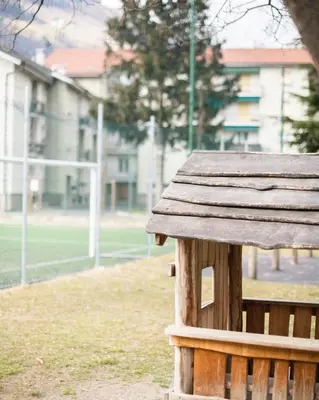a wooden bench in front of a soccer field at Stay City in MeranO with Bio Sauna in Merano