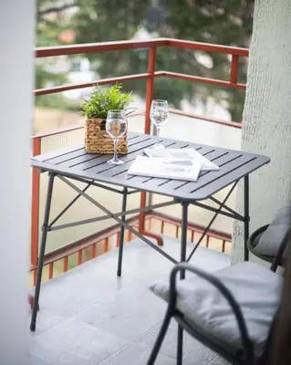 a table on a balcony with two glasses of wine at Stay City in MeranO with Bio Sauna in Merano