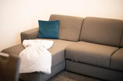 a brown couch with a blue pillow in a room at Stay City in MeranO with Bio Sauna in Merano