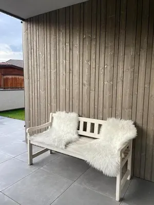 a white bench with furry cushions sitting on a patio at Apartment Malfi in Fiè