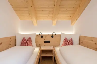 two beds in a small room with wooden ceilings at Bäckerhof in Tesido