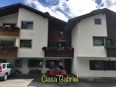 a white building with cars parked in front of it at Ciasa Gabriel in Colfosco
