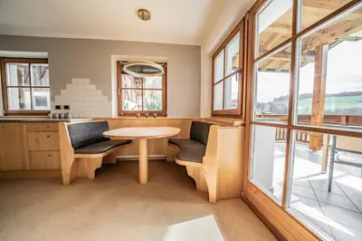 a kitchen with a table and chairs and windows at Apartment Misalt in Castelrotto