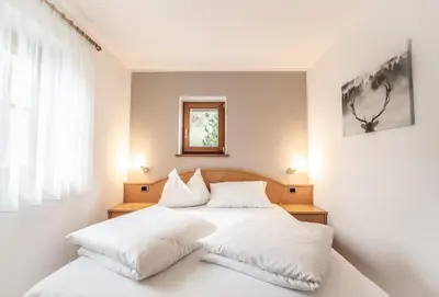 a bedroom with a white bed with white pillows at Apartment Misalt in Castelrotto