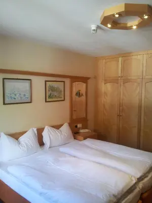 a bedroom with a large bed with white sheets at B&B Chalet Brigitte Hike & Bike in Arabba
