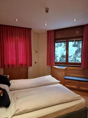 two beds in a room with red curtains at B&B Chalet Brigitte Hike & Bike in Arabba