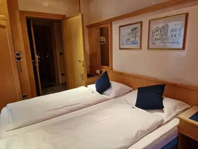 a large white bed with two blue pillows on it at B&B Chalet Brigitte Hike & Bike in Arabba