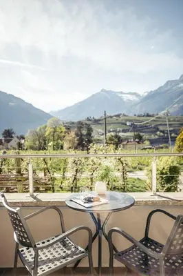 a table and chairs on a balcony with a view of mountains at Suite Mais in Merano