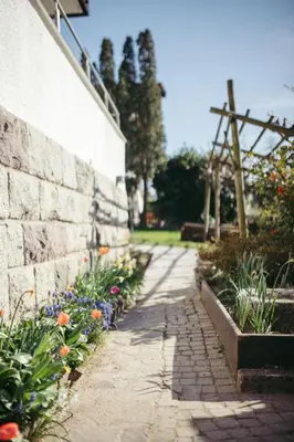 a stone wall and a path with flowers at Suite Mais in Merano
