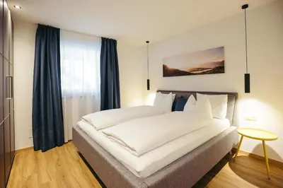 a bedroom with a large white bed and a table at Suite Mais in Merano