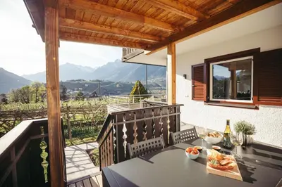 a table on a balcony with a view of the mountains at Suite Mais in Merano