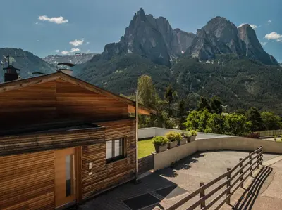 a wooden house with mountains in the background at Appartment Waldrand in Castelrotto