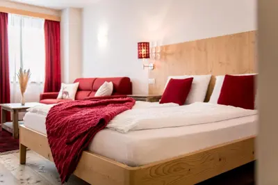 a bedroom with a large bed with red accents at Am Schloss Guest House in Brunico