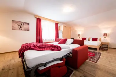 a large bedroom with two beds and a couch at Am Schloss Guest House in Brunico