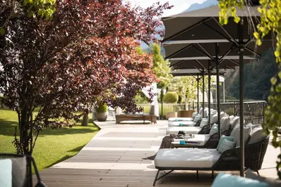 a row of chairs and tables under an umbrella at Hotel Chalet Das Alpenschlössel in Saltusio