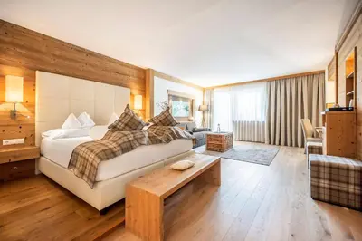 a bedroom with a bed and a table in a room at Hotel Chalet Das Alpenschlössel in Saltusio