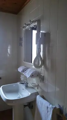 a white bathroom with a sink and a mirror at Chalet Helen in Arabba