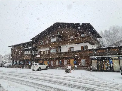 a snow covered building with a car parked in front of it at Chalet Helen in Arabba