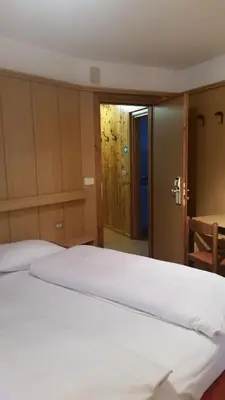 a large white bed in a room with a door at Chalet Helen in Arabba