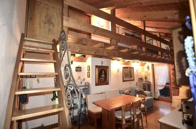 a dining room with a wooden table and a staircase at Cozy attic in the center of San Vito in San Vito di Cadore