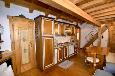 a kitchen with wooden cabinets and a table in a room at Cozy attic in the center of San Vito in San Vito di Cadore