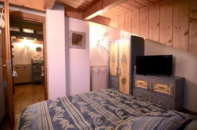 a bedroom with a bed and a flat screen tv at Cozy attic in the center of San Vito in San Vito di Cadore