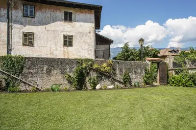 an old house with a stone wall and a yard at Apartment Residence Veronika in Ora/Auer