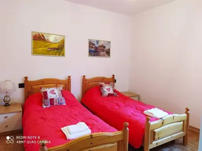 two beds in a bedroom with red sheets at La casa dello scoiattolo primierotto in Tonadico
