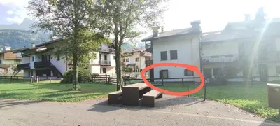 a red circle sitting on a bench in front of a building at La casa dello scoiattolo primierotto in Tonadico