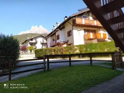 a house with a fence in front of a street at La casa dello scoiattolo primierotto in Tonadico